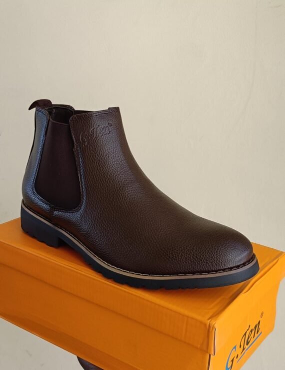 A high-quality, stylish Chelsea boot in a dark brown color, displayed on a bright orange shoebox. The boot features a classic Chelsea design with a contrasting brown leather upper and a contrasting black rubber outsole.